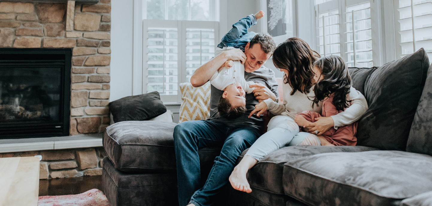 Family laughing on couch together in cozy living room